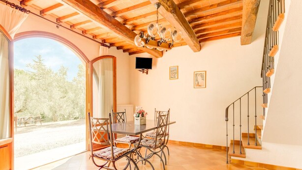 A dining area with a table and chairs, a chandelier, and a staircase. - Belvilla by OYO Casanova Dependance (Gambassi Terme)