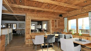 A wooden interior with a dining area, kitchen, and large windows with curtains. - Unique Large Alpine Pasture in the Middle of the Zillertal Mountains (Zellberg)