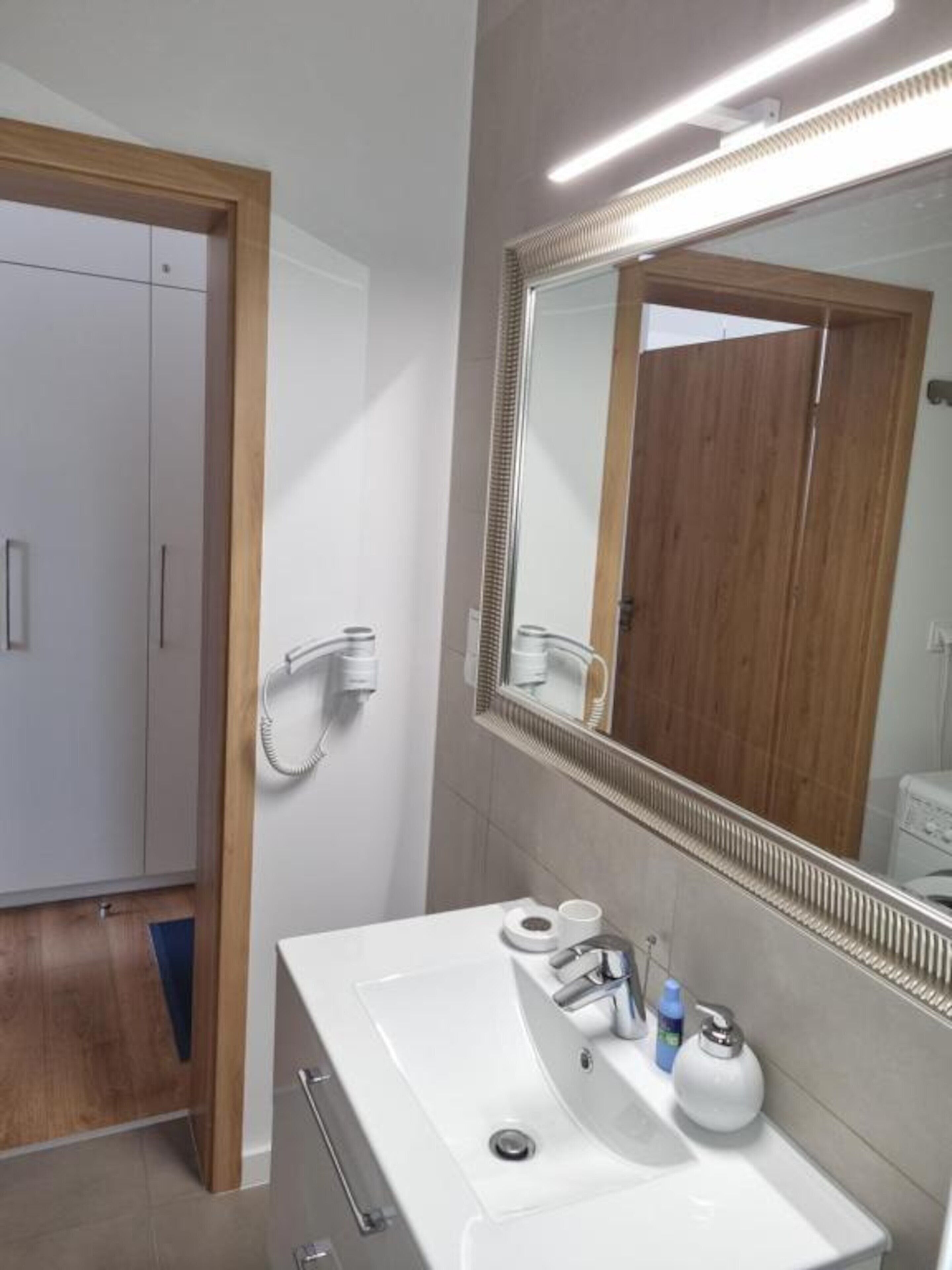 A modern bathroom with a white sink, mirror, and towel rack.