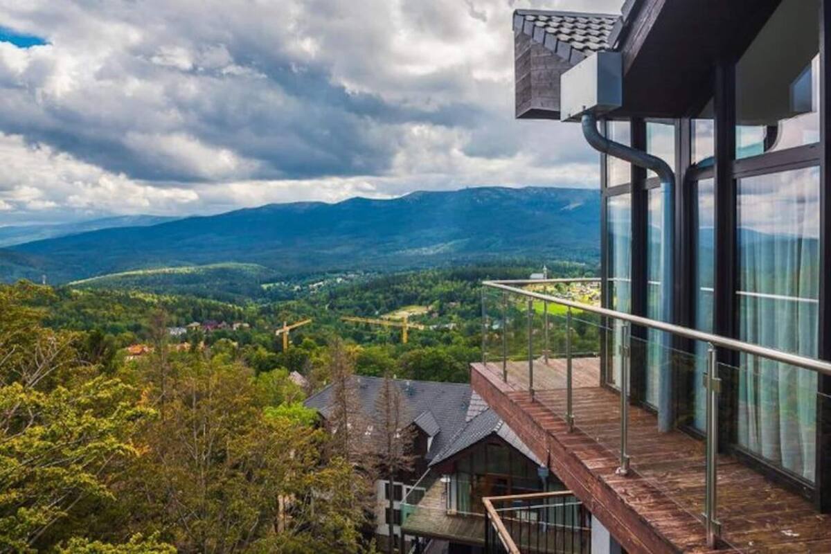 Ein modernes Gebäude mit großen Fenstern und Blick auf eine gebirgige Landschaft.