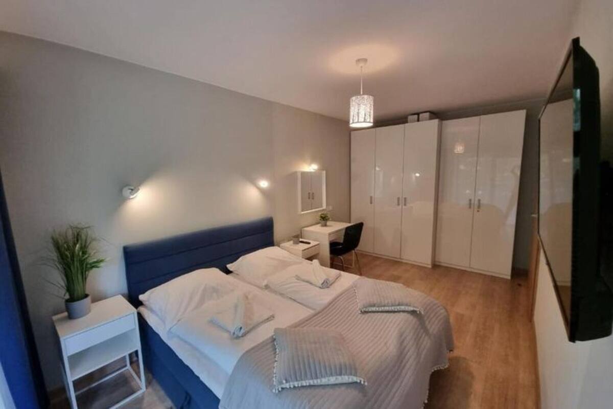 Ein modernes Schlafzimmer mit einem großen Bett, Nachttischen, einem Schreibtisch und einem Kleiderschrank.