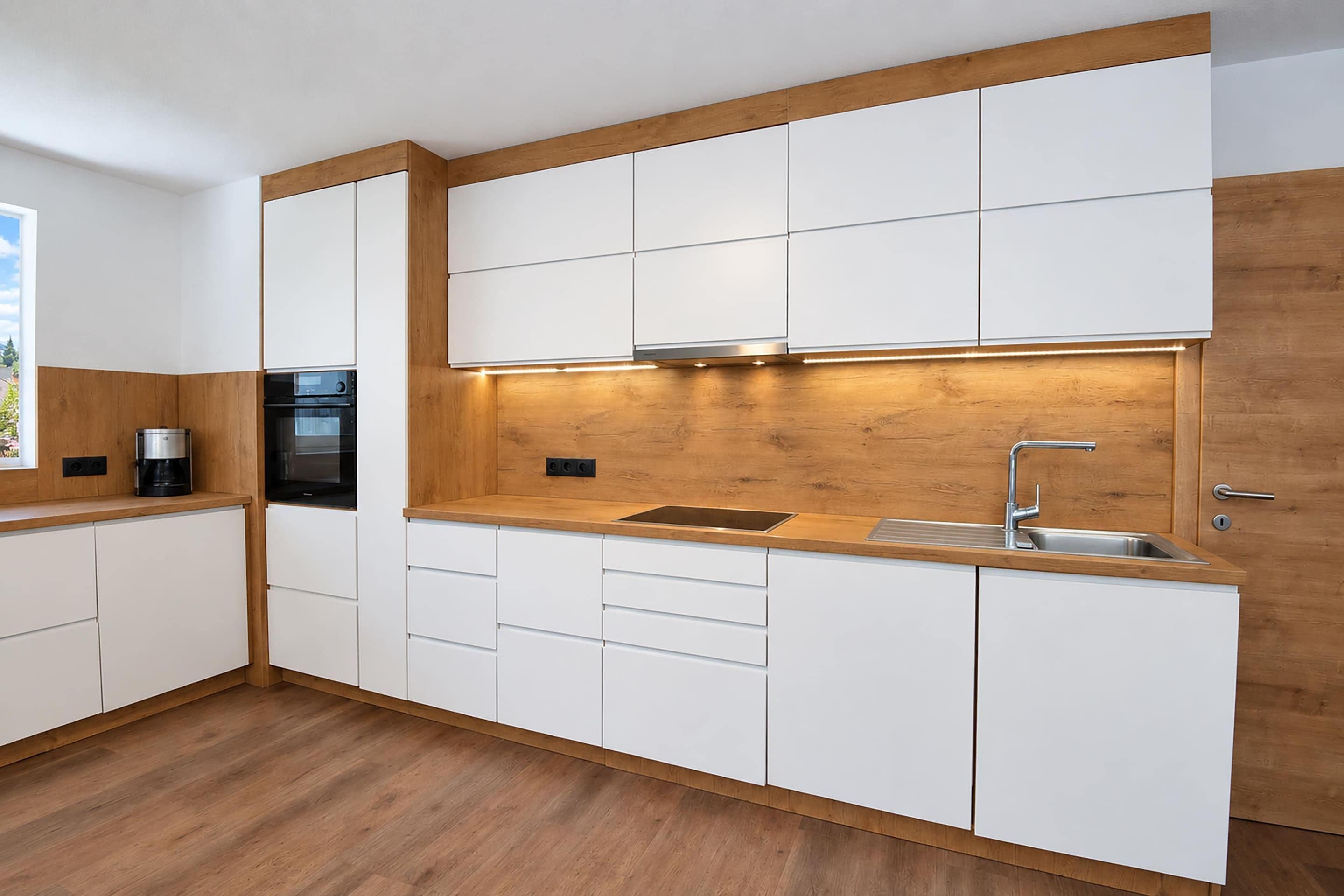 A modern kitchen with white cabinetry, a wooden countertop, and a built-in oven.