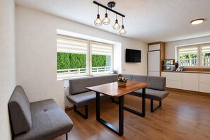 A modern kitchen with a dining area, wooden flooring, and a view of greenery outside. - Holiday Home Bergheim, Fugen (Fuegen)
