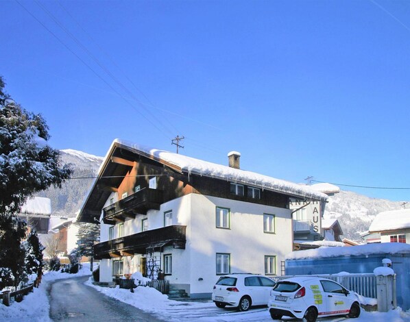 A two-story building with a sloped roof, a wooden balcony, and a snow-covered ground. - Holiday Home Bergheim, Fugen (Fuegen)