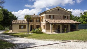 A two-story house with a tiled roof, a covered patio, and a gravel driveway. - Belvilla by OYO Villa Vanessa Coccinella (Fano)