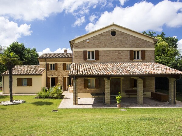 A two-story house with a tiled roof, a covered patio, and a well-maintained lawn. - Belvilla by OYO Villa Vanessa Coccinella (Fano)
