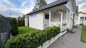A white building with a porch, a sign reading "MAVII", and a well-maintained lawn.
