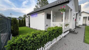 A white building with a porch, a sign reading "MAVII", and a well-maintained lawn.