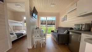 A cabin with a bunk bed, a sofa, a dining area, and a kitchen with a microwave.