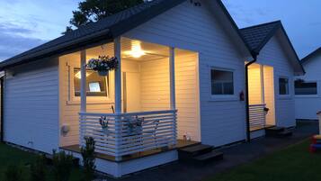 A white single-story house with a porch, a small window, and a door.