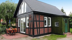 A traditional half-timbered house with a sloped roof, a green door, and a patio with a table and chairs. - Holiday Home Haffschein, Monkebude (Monkebude)