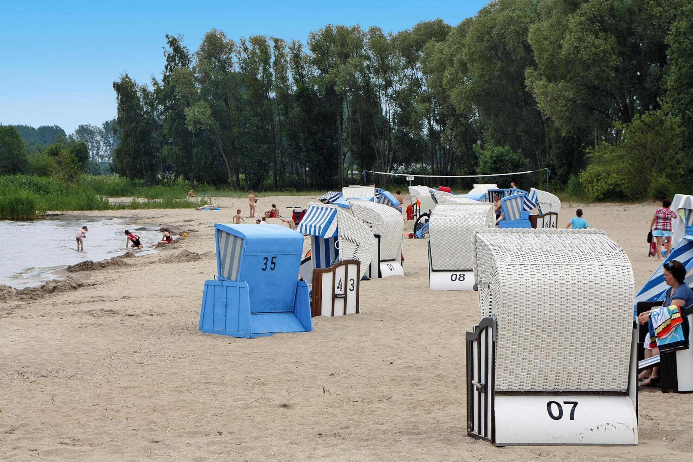 Beach huts numbered 35, 43, 07, and 08, with a volleyball net in the background.