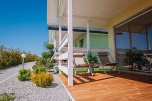 A modern building with a wooden deck, outdoor seating, and a covered area. - Family Holiday Resort, Holiday Houses, Bobolin (Darlowo)
