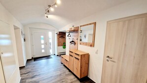A hallway with wooden flooring, a wooden wardrobe, a mirror, and a coat rack.