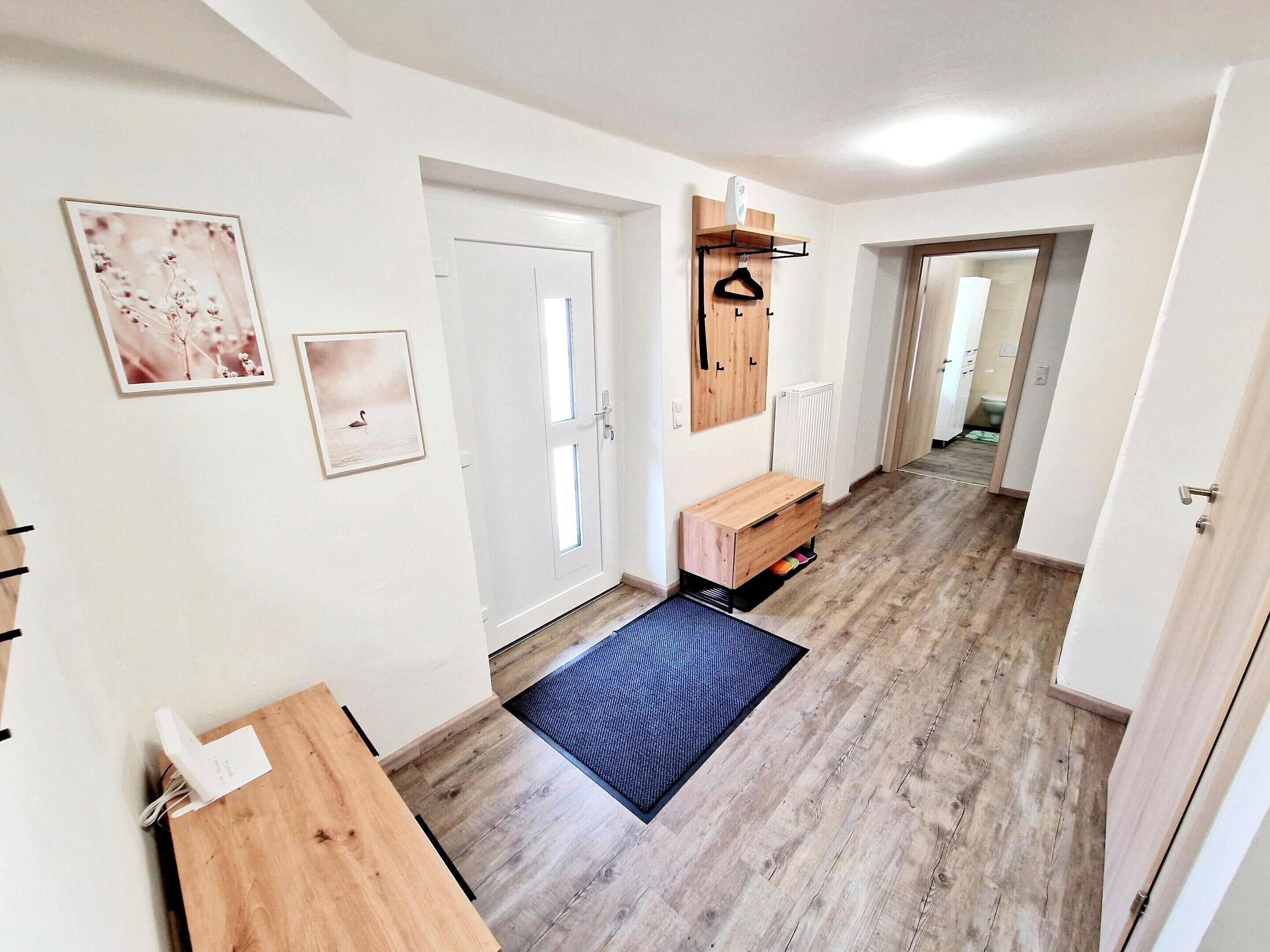 A hallway with wooden flooring, a bench, a door, and a radiator.