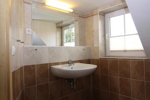 A bathroom with a sink, mirror, and window.