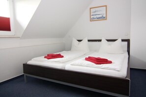 A twin bed with white bedding and red towels, a wooden headboard, and a framed picture on the wall. - Semi-detached House, Kuehlungsborn (Kuehlungsborn)