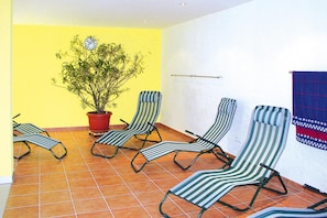 A room with four striped lounge chairs, a potted plant, and a blue and red patterned towel on the wall. - Semi-detached House, Kuehlungsborn (Kuehlungsborn)