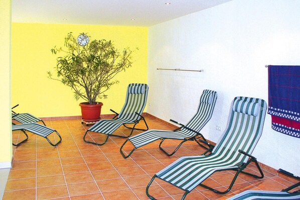 A room with four striped lounge chairs, a potted plant, and a blue and red patterned towel on the wall. - Semi-detached House, Kuehlungsborn (Kuehlungsborn)