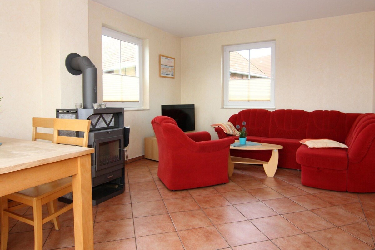 A living room with a fireplace, a TV, a red sofa, and a wooden table.