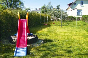 Ein Spielplatz mit rotem Rutsche und Schaukeln auf einer grünen Wiese.
