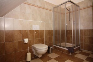 Ein Badezimmer mit Toilette, Dusche und Fliesenboden.
