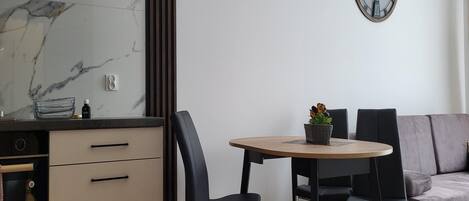 Une cuisine moderne avec un revêtement mural en marbre, un four encastré et un coin repas comprenant une table ronde et des chaises.