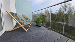 A balcony with two wooden lounge chairs and a potted plant. - Comfy Apartment Near the sea in Gaski (Mielno)