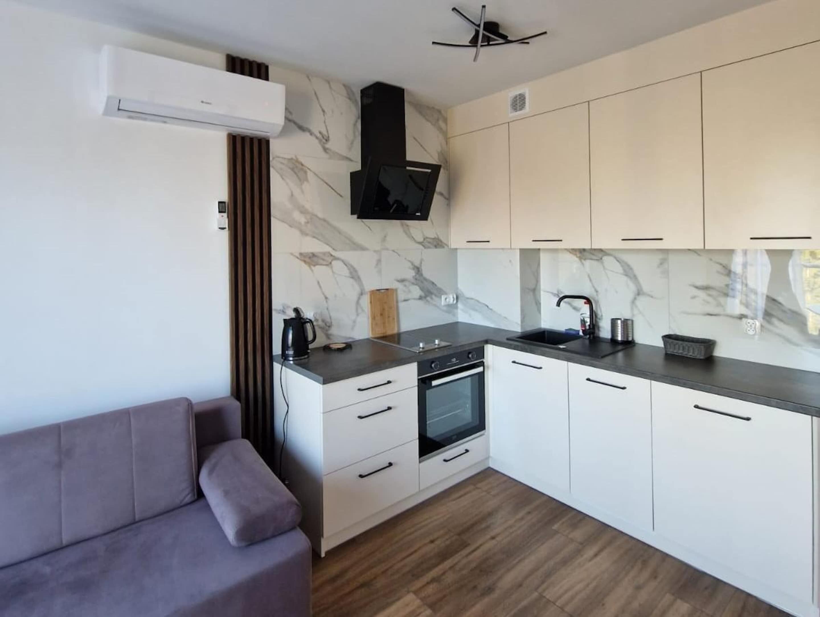 A modern kitchen with white cabinets, a built-in oven, and a grey countertop.