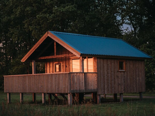 A wooden cabin with a balcony, a metal roof, and a wooden deck. - Atmospheric Lodge With Unobstructed View, Located in Beautiful Drenthe (Ruinerwold)