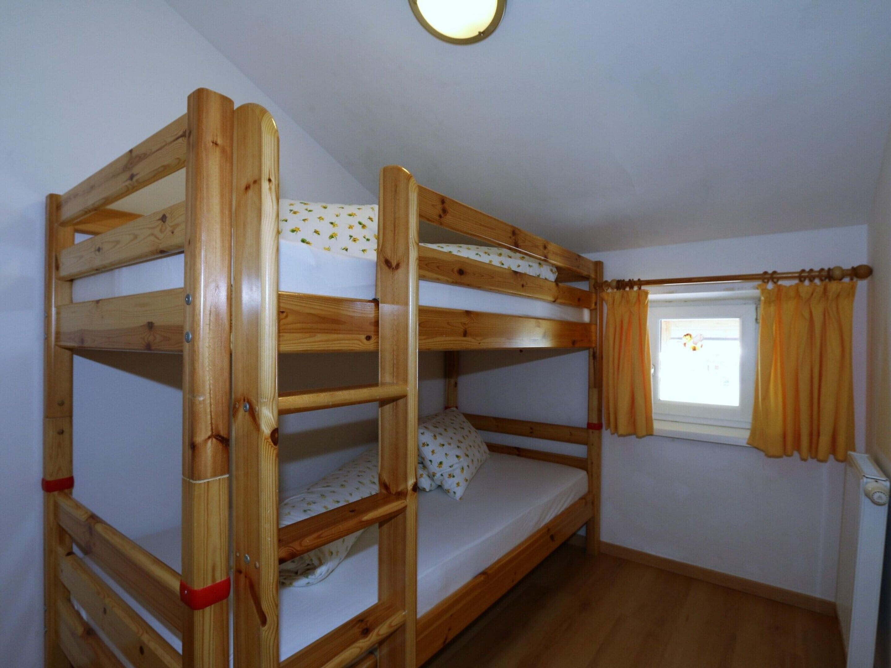 A bunk bed room with a window and curtains.
