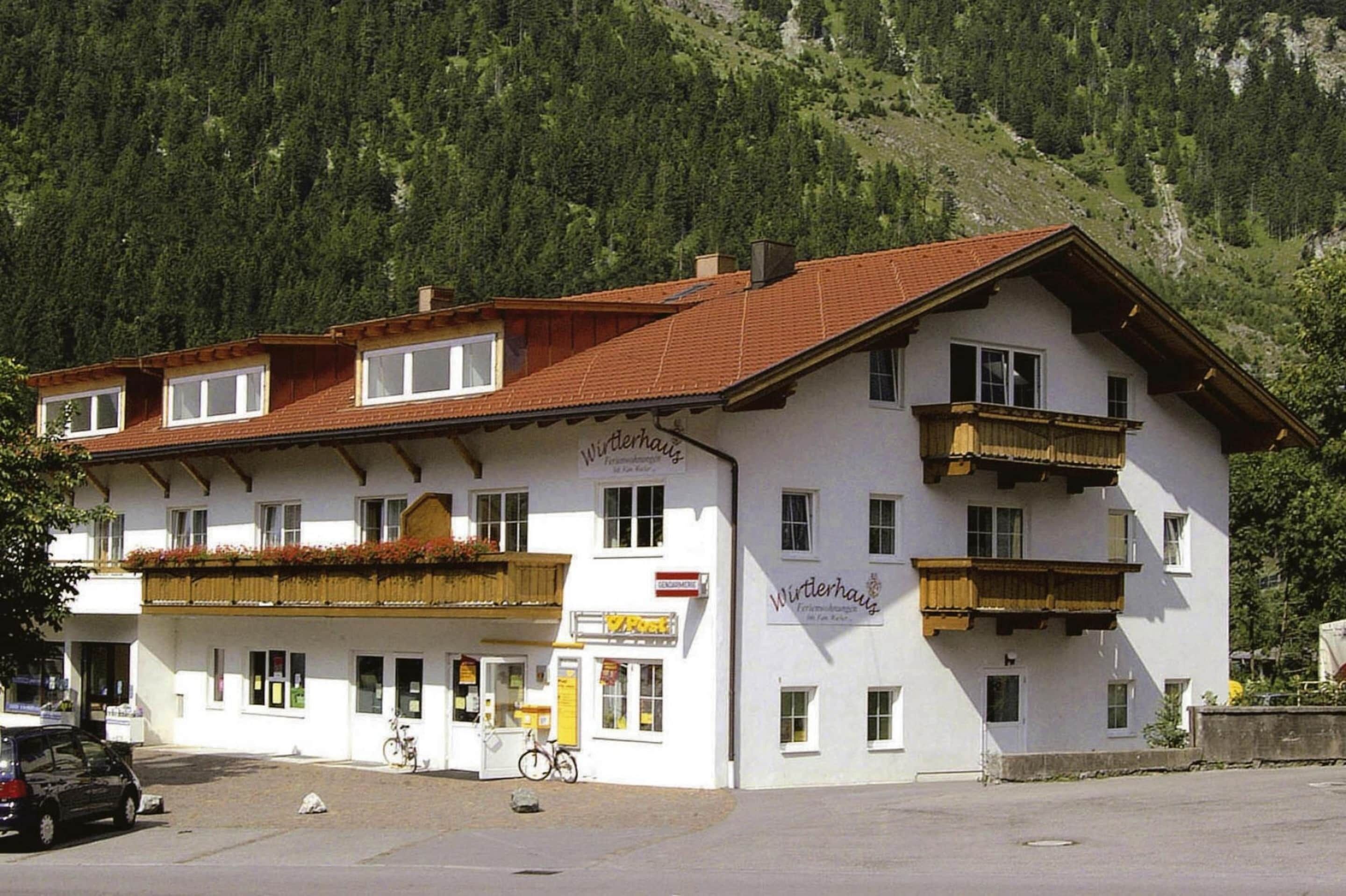 Un edificio de dos pisos con techo de tejas rojas, balcones con barandillas de madera y un letrero que dice "Winterhaus".