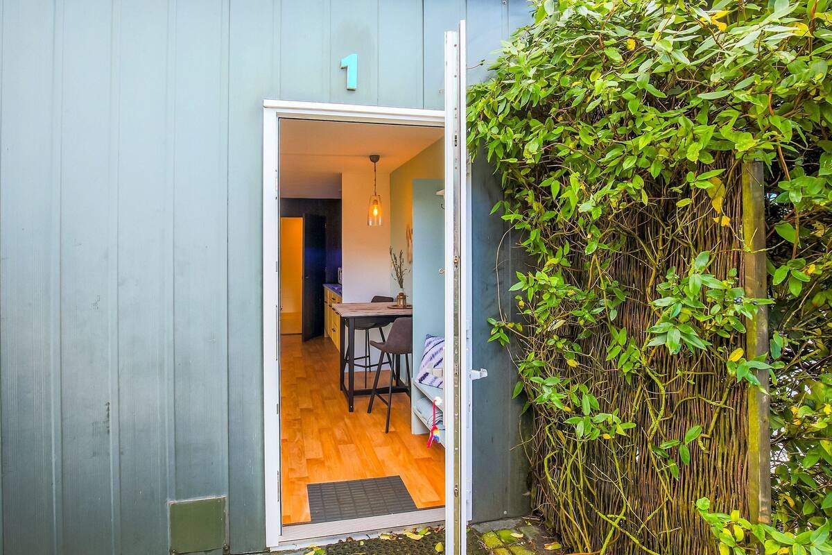 Een deur die leidt naar een kamer met een houten vloer en een eettafel.