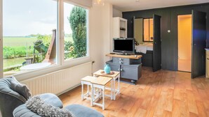 Ein modernes Wohnzimmer mit großem Fenster, einer Couch, einem Fernseher und einem kleinen Tisch.