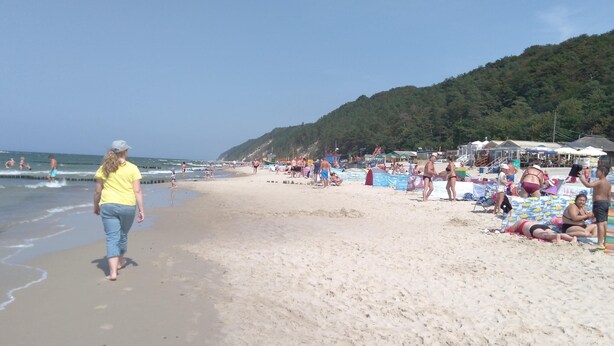 A beach with people walking and sunbathing. There are umbrellas and beach chairs set up. - New Holiday Homes for 2 People in Dziwnowek (Kamien Pomorski)
