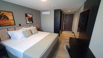 A hotel room with a large bed, a desk, a TV, and artwork on the walls.