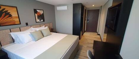 Habitación de hotel con una cama grande, un escritorio, un televisor y obras de arte en las paredes.