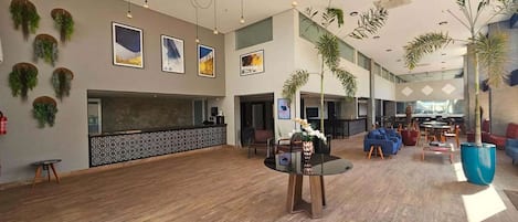 A spacious lobby with a reception desk, seating area, and decorative plants.