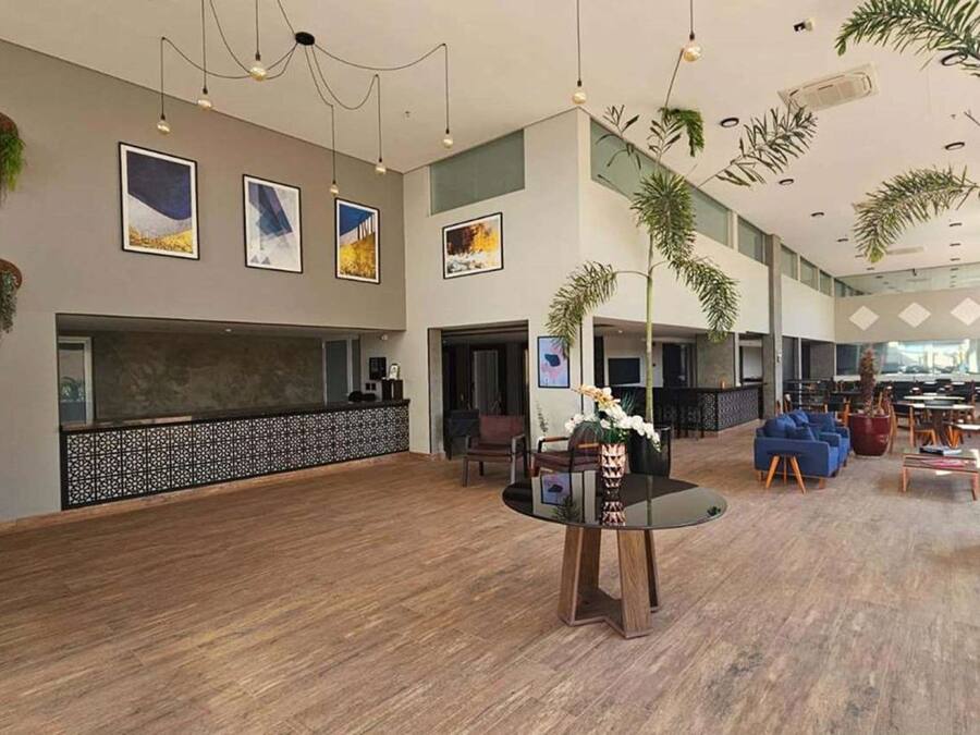 Een ruime lobby met een receptiebalie, zithoek en decoratieve planten.