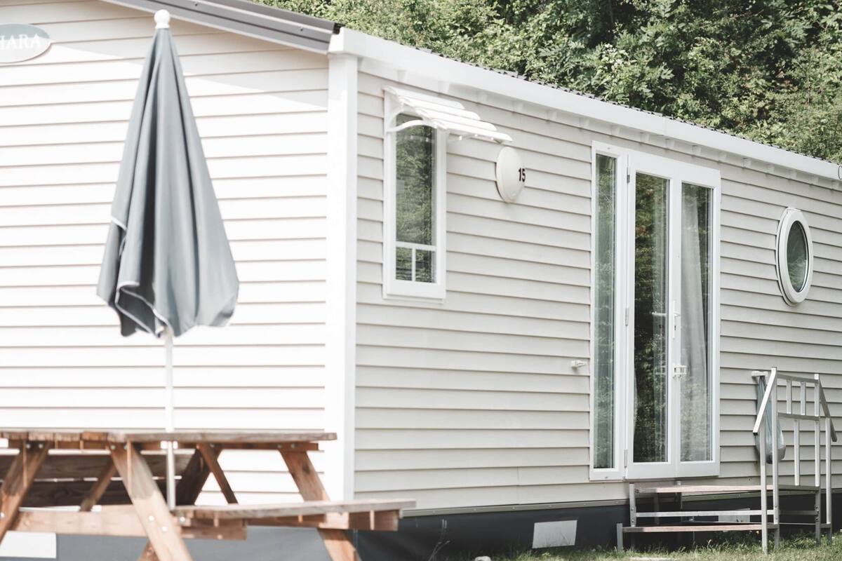 A mobile home with a picnic table and an umbrella.