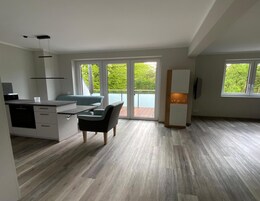 Eine moderne Küche mit Essbereich, großen Fenstern und Blick auf Grünflächen.