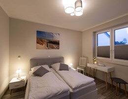 Ein Schlafzimmer mit Bett, Nachttischen, einem Schreibtisch und einem Fenster.