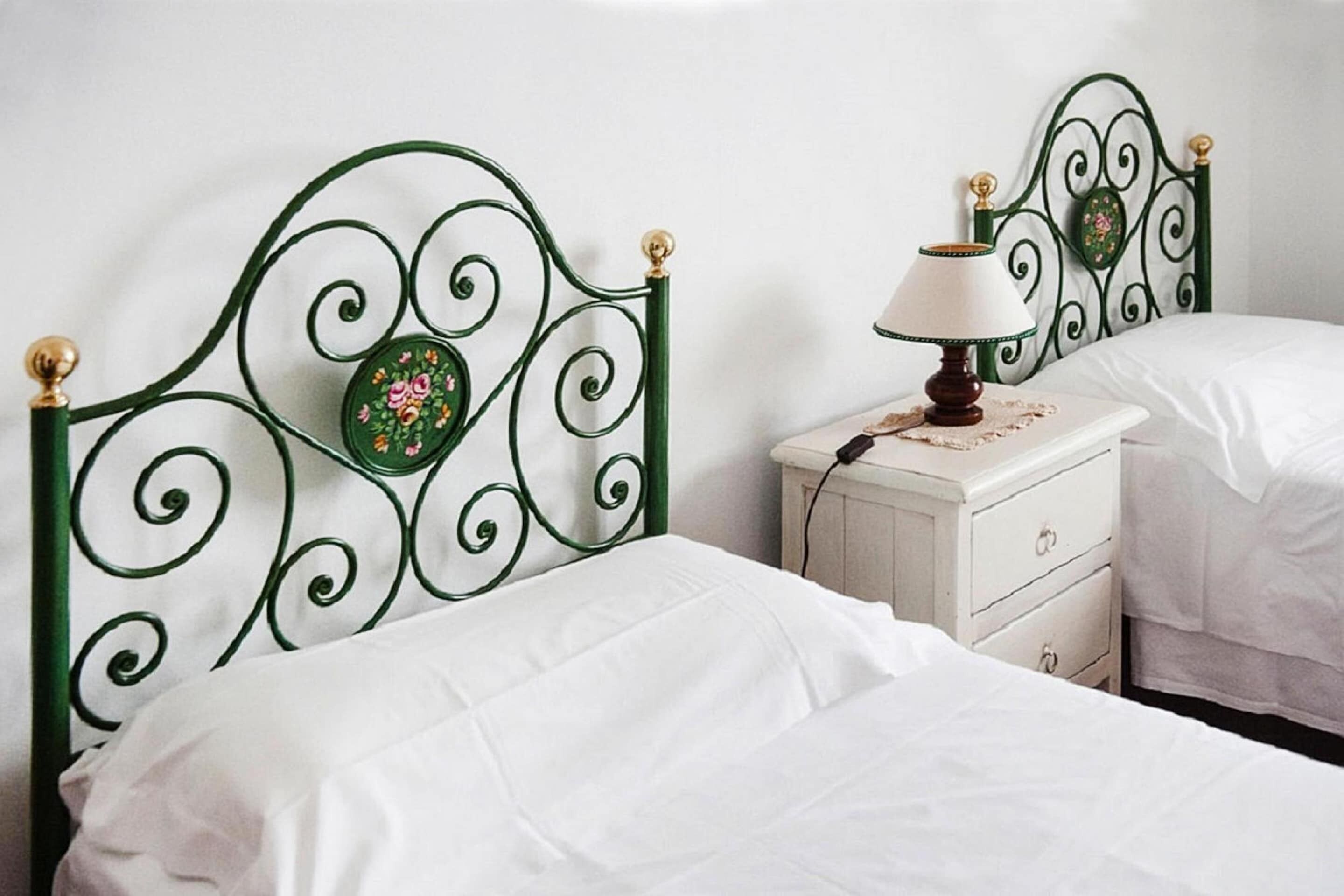 A bedroom with two single beds, a nightstand with a lamp, and a decorative headboard.