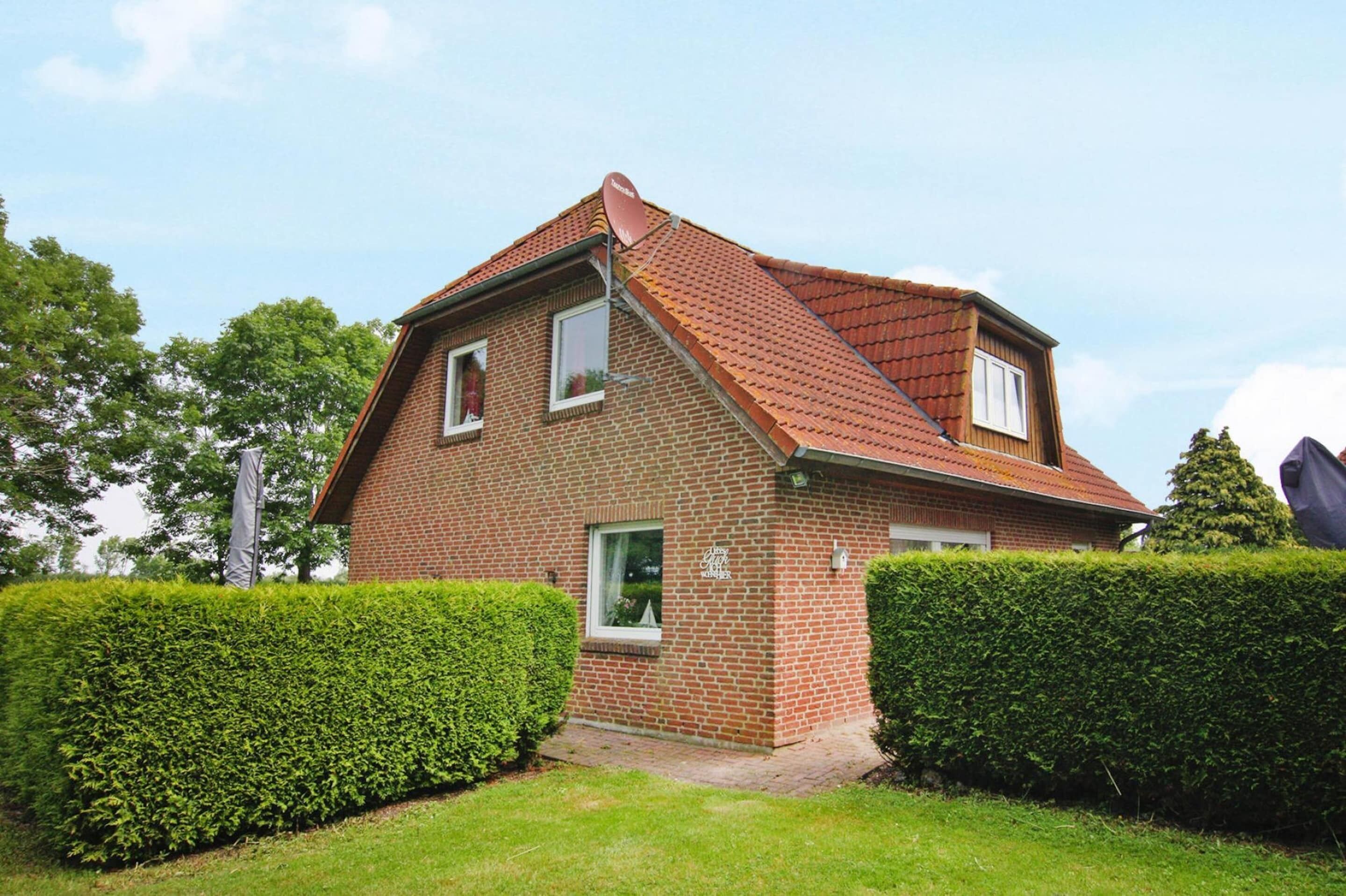 A two-story brick house with a sloped roof, a small front porch, and a well-maintained hedge.