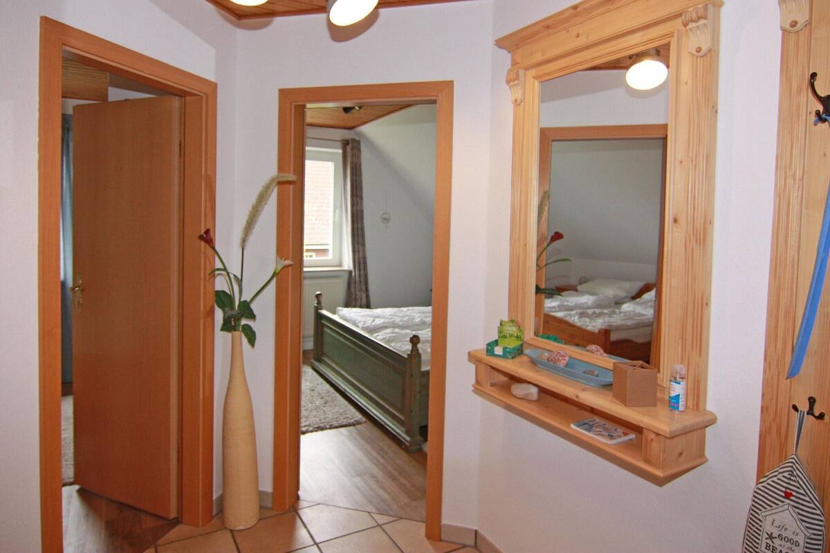 Un dormitorio con una cama de madera, una mesita de noche con espejo y un pequeño estante con artículos de aseo.