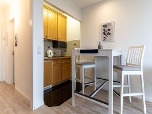 A compact kitchen with wooden cabinets, a microwave, a kettle, and a small table with two chairs. - Apartment in St. Peter-ording (St. Peter-Ording)