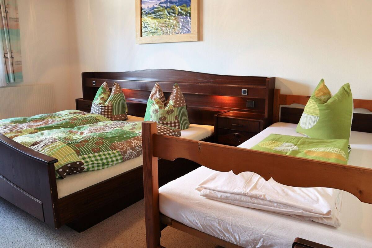 Habitación de hotel con dos camas, cada una con cabecero de madera, mesita de noche y un cuadro en la pared.