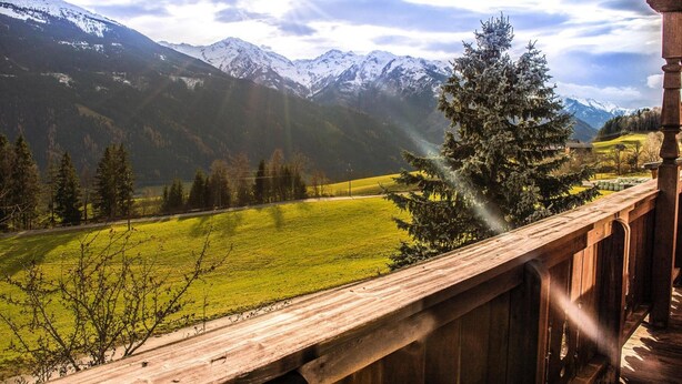A mountain landscape with a wooden balcony overlooking a green field and snow-capped peaks. - Rauchenbacher Apartments, Mittersill (Mittersill)