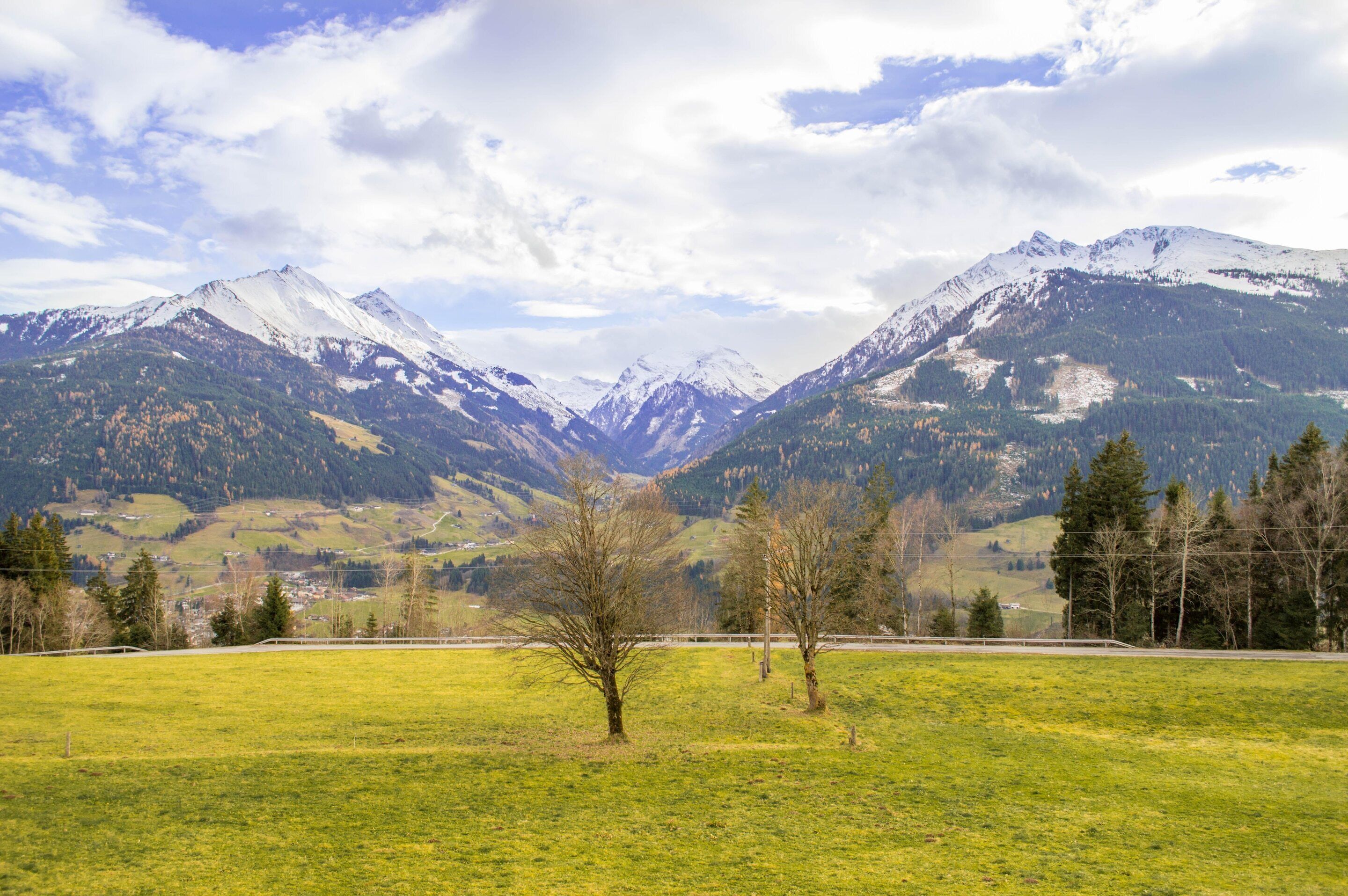 A mountainous landscape with snow-capped peaks, a grassy foreground, and a clear sky.