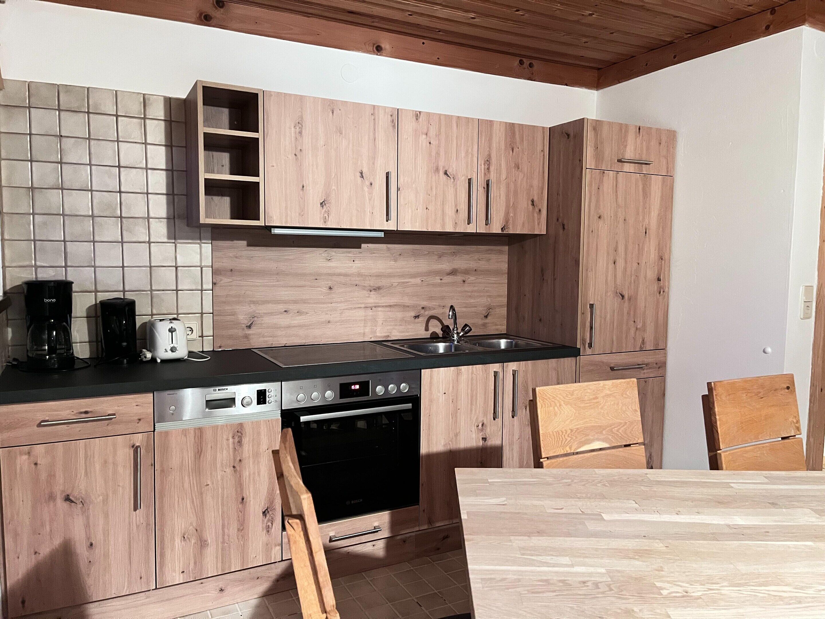 A kitchen with wooden cabinets, a Bosch dishwasher, a sink, and a wooden table.